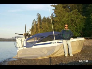 Bryan Phillips standing beside his Explorer 20 hovercraft on a beach, January 1998