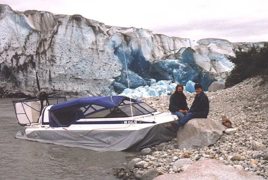 The Explorer 20 prototype hovercraft parked on rocks below the ice face of the Taku Glacier, with two people beside it