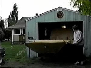 The bare Explorer 20 prototype hull being rolled out of the small rented garage where it was built, 1995