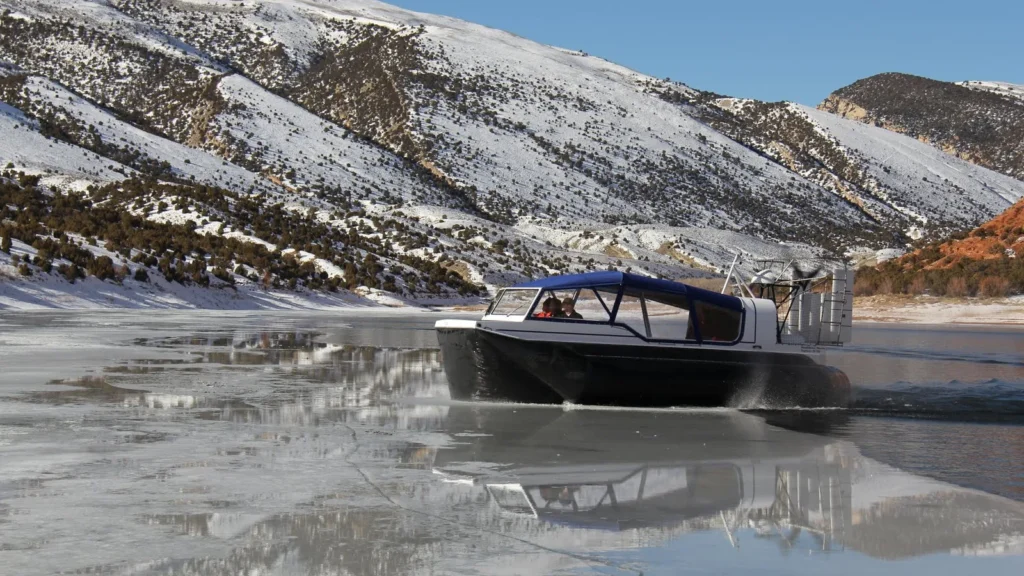 Daggett County SAR Explorer 22 TDi hovercraft running across the ice below snowy hills at Flaming Gorge