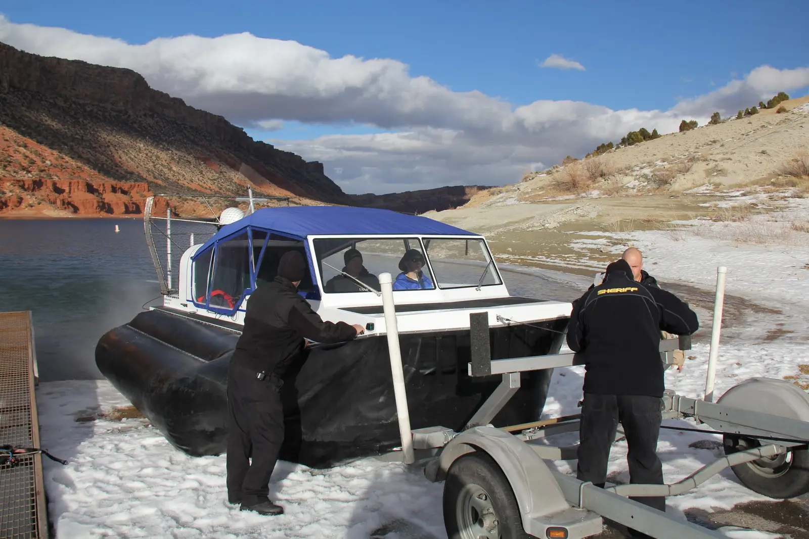 Two people guiding an Explorer 22 onto its trailer on an icy shore