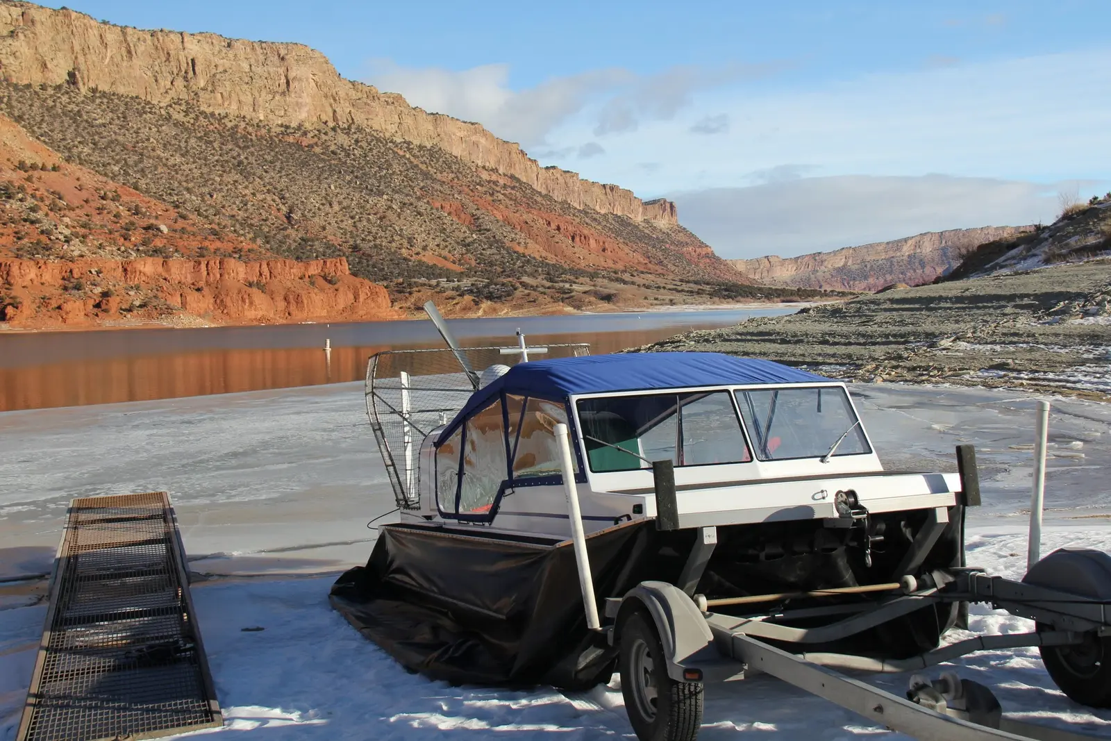 Explorer 22 hovercraft on the ice beside its trailer at the foot of a snowy ramp