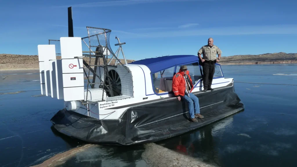 Daggett County SAR Explorer 22 TDi on clear ice at Flaming Gorge, a deputy standing on the deck and a crew member seated on the side