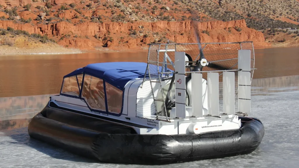 Daggett County SAR Explorer 22 TDi hovering on the ice at Flaming Gorge, red rock behind