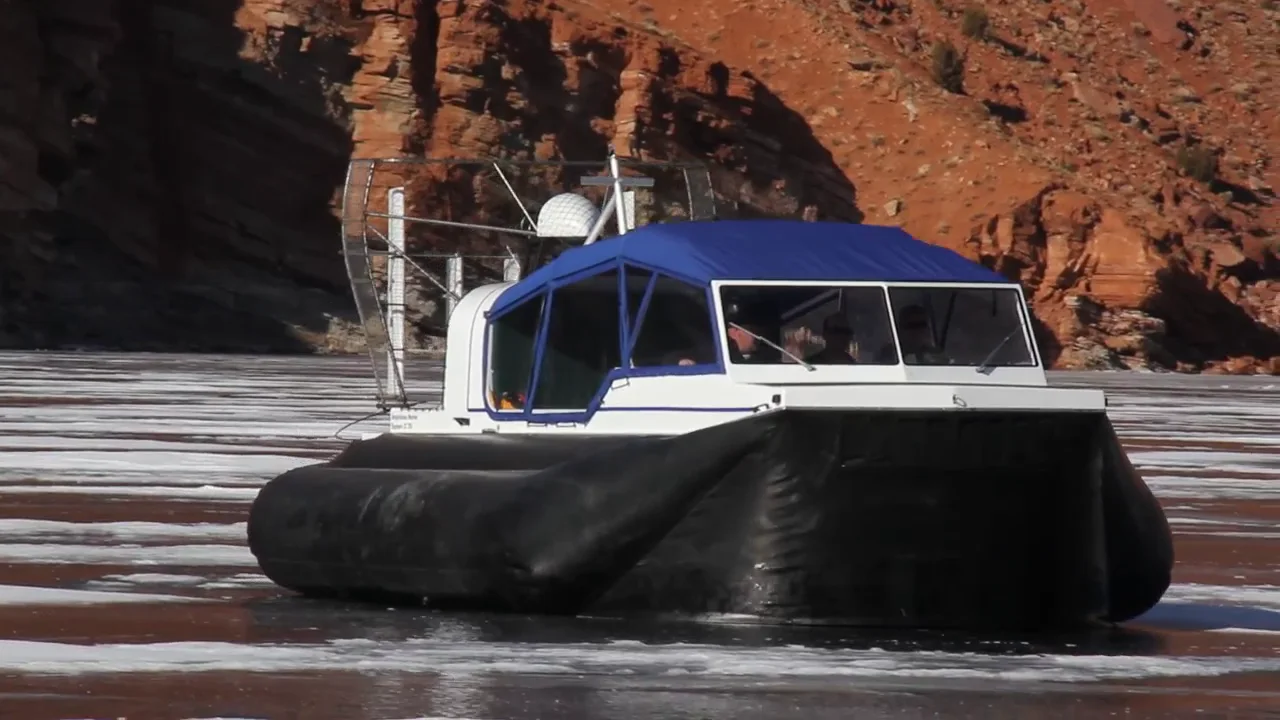 Daggett County SAR Explorer 22 TDi hovering on the ice at Flaming Gorge, skirt full, red cliffs behind
