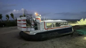 Explorer 24 on the shore at dusk with lights on