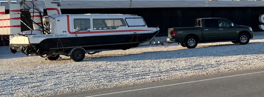 An Explorer 24 hovercraft on its road trailer behind a pickup truck in Texas
