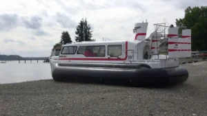 Explorer 24 on a gravel shore with trees behind