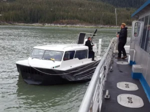 Explorer 24 alongside a larger vessel with a passenger stepping across
