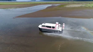 Explorer 24 crossing a tide flat with spray and a rainbow