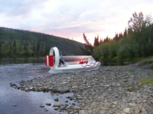 A white Geoduck 16 hovercraft on a river gravel bar at sunset