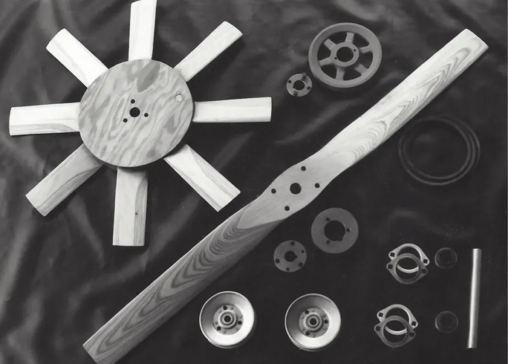 Hand laminated wooden propeller, lift fan and drive pulleys laid out on a black background