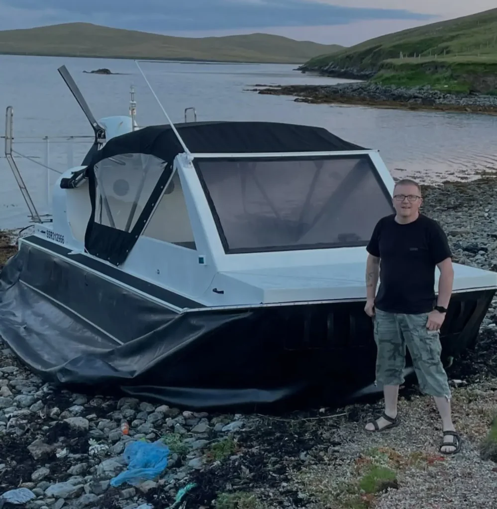 Mark standing beside his gas powered Explorer 22 on a Shetland beach