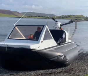 Two people aboard Mark's Explorer 22 at the water's edge, seen from the bow