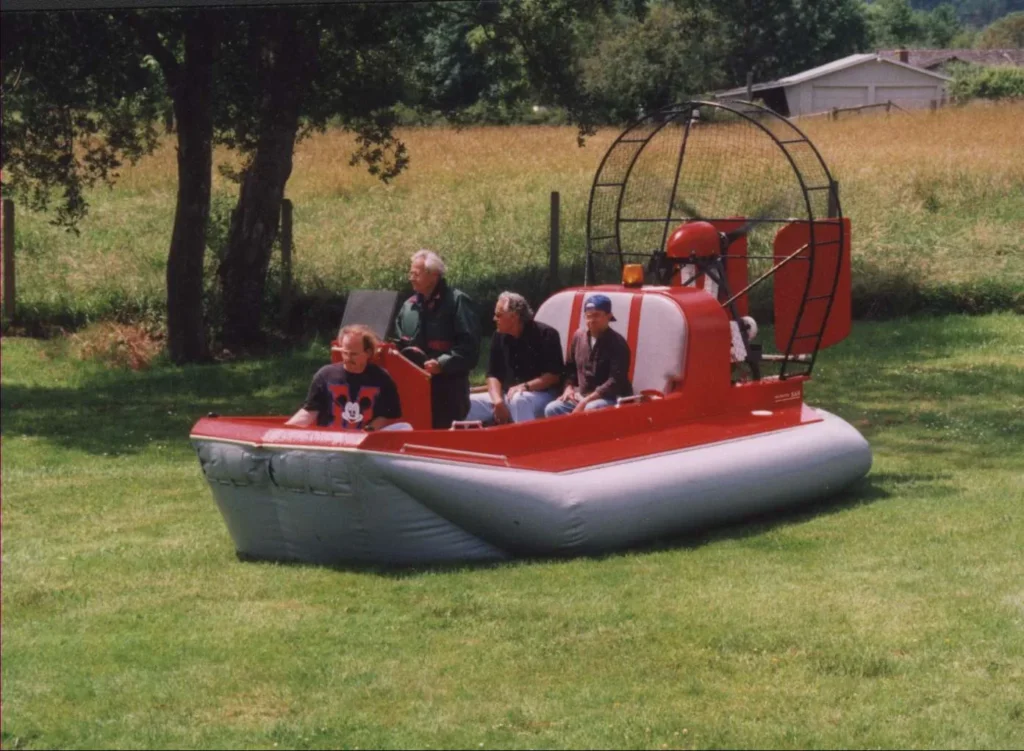 Four people aboard the Prospector rescue hovercraft on a grass field