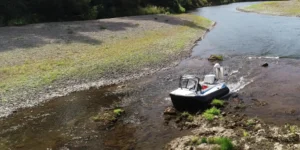 Surveyor 16 hovercraft climbing onto a rock ledge in a shallow river beside a gravel bar