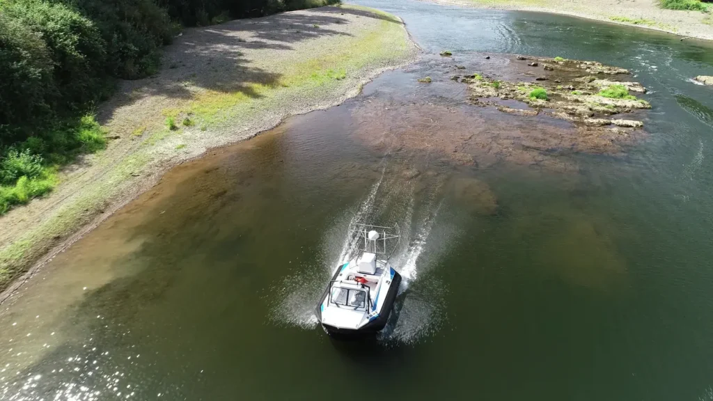 Surveyor 16 hovercraft running up a shallow river past a gravel bar