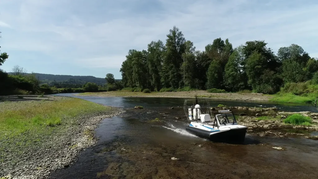 Surveyor 16 hovercraft crossing a shallow, rocky stretch of river beside a gravel bar