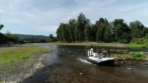 Surveyor 16 hovercraft crossing a shallow, rocky stretch of river beside a gravel bar