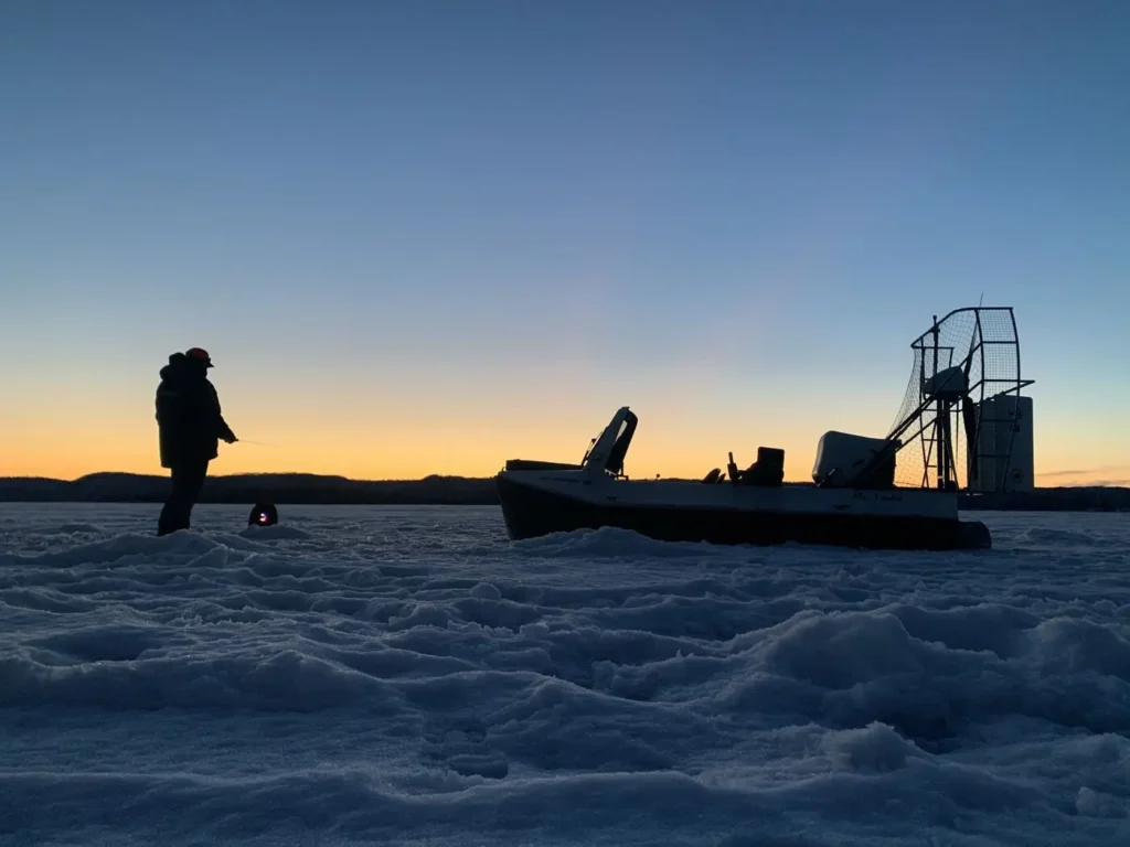 Surveyor 16 on the ice at dusk with an angler ice fishing