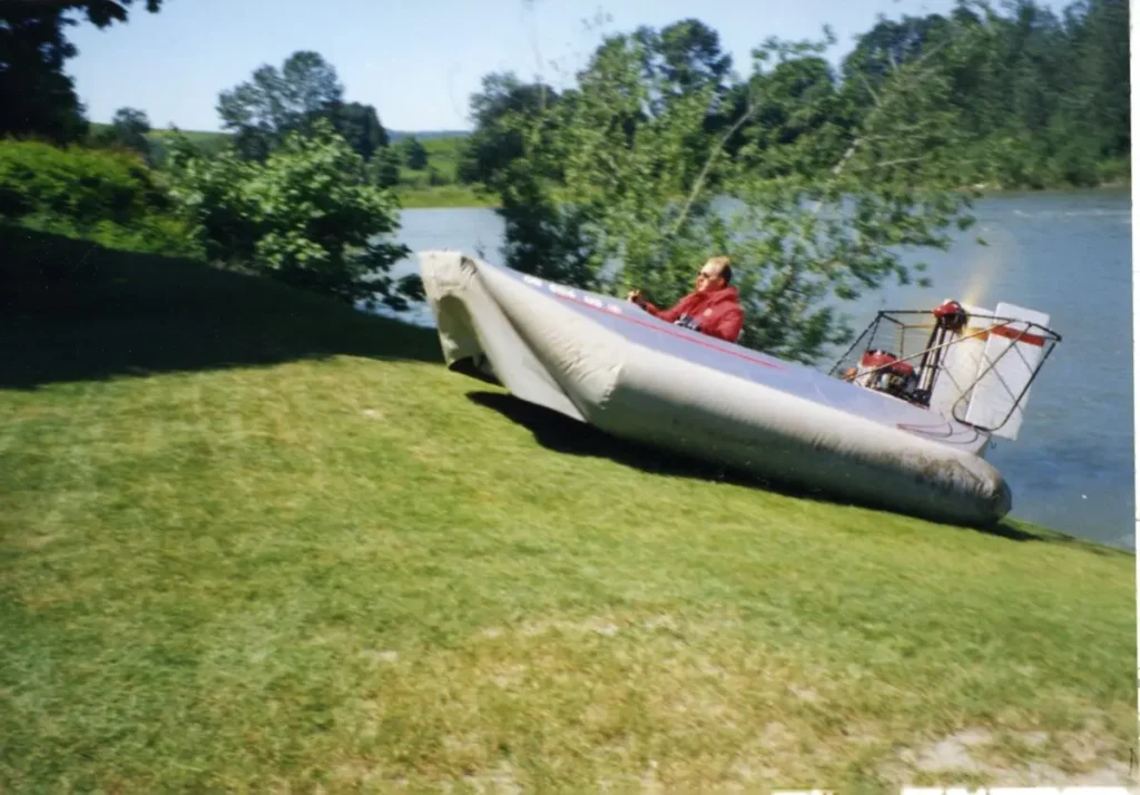 A Vanguard 14 hovercraft driving up a grassy riverbank, 1993