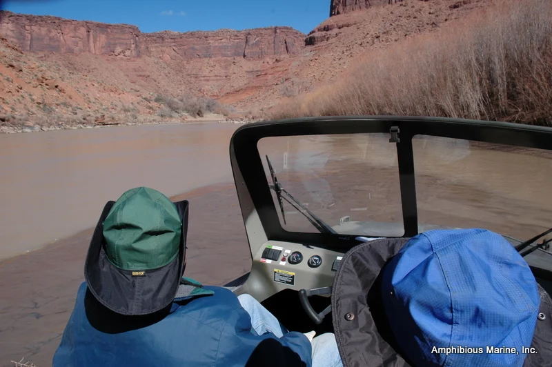 View from a Vanguard hovercraft cockpit on a desert river below red canyon walls